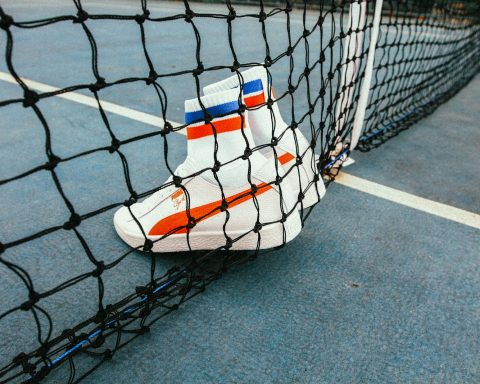 white-and-red Puma Sock shoes on tennis net