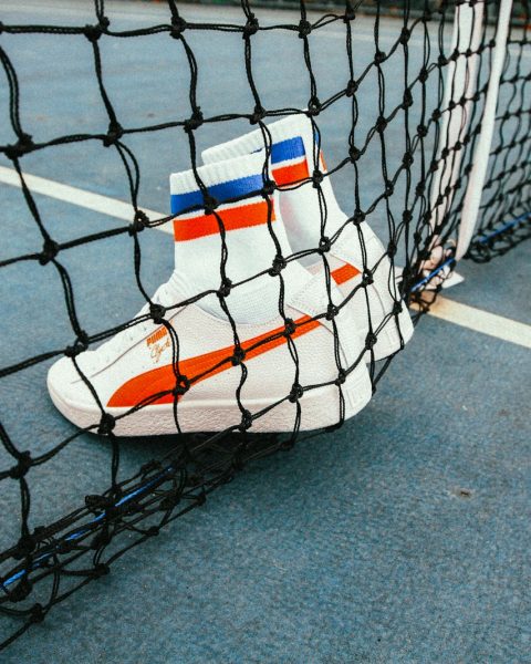 white-and-red Puma Sock shoes on tennis net