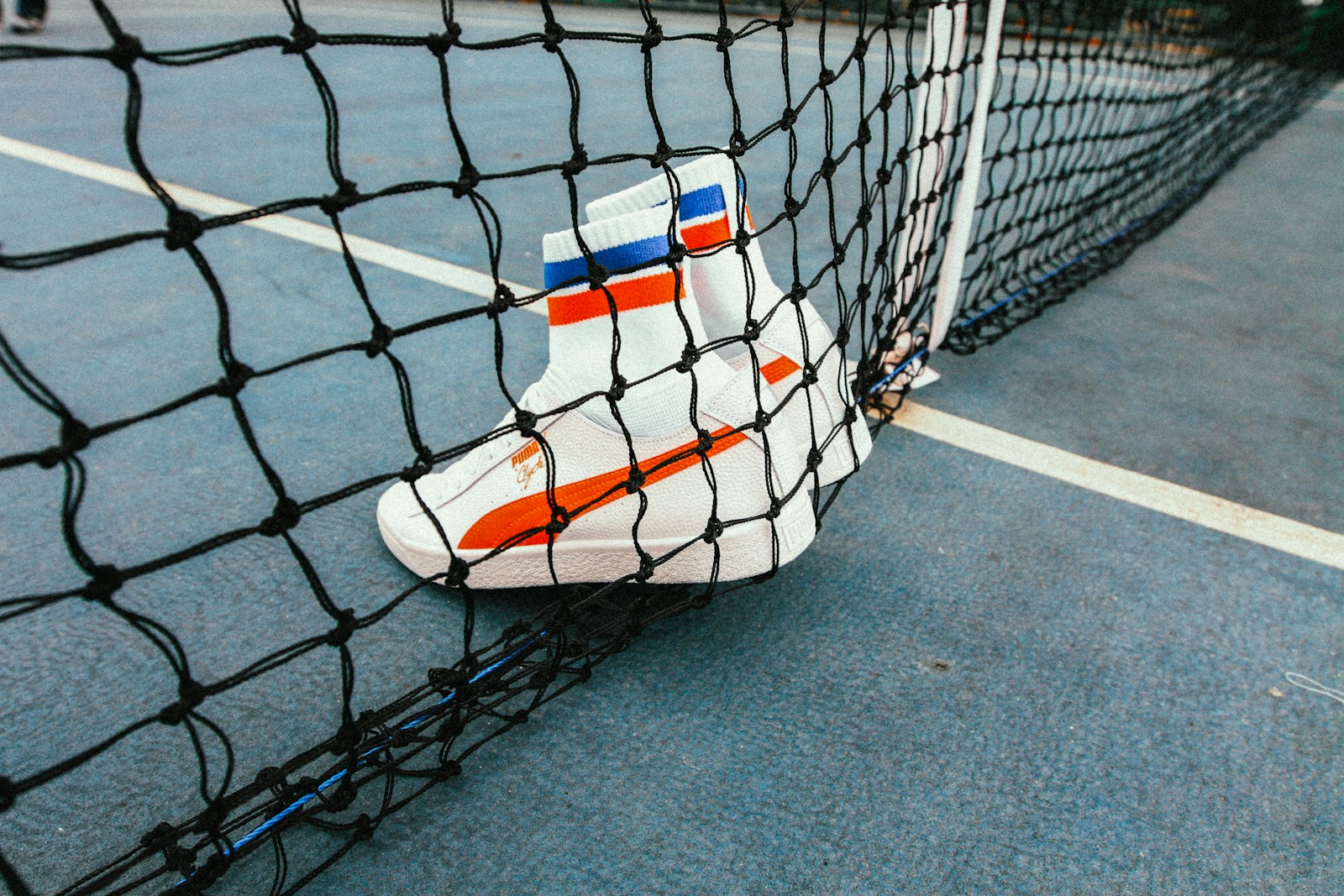 white-and-red Puma Sock shoes on tennis net