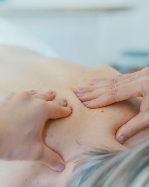 person massaging the back of a woman
