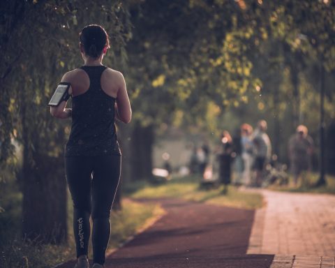 woman in black tank top and black pants walking on sidewalk during daytime