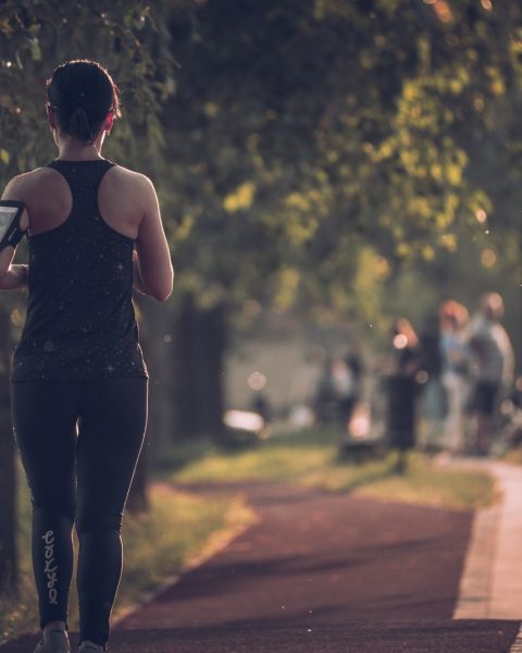 woman in black tank top and black pants walking on sidewalk during daytime