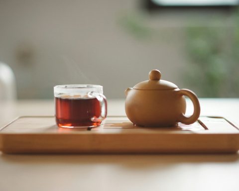 clear glass cup with tea near brown ceramic teapot