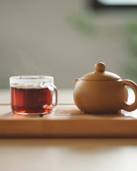 clear glass cup with tea near brown ceramic teapot