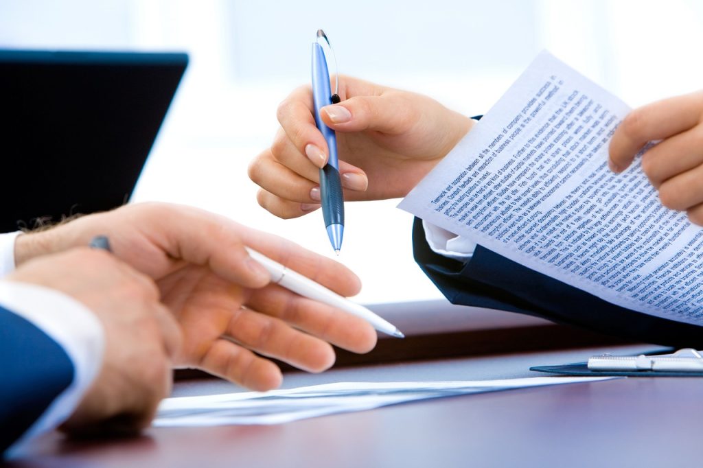 Jonge vrouw die haar arbeidscontract en loonstrook doorleest aan een bureau