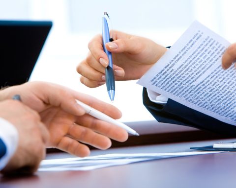 Jonge vrouw die haar arbeidscontract en loonstrook doorleest aan een bureau