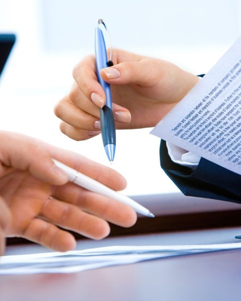 Jonge vrouw die haar arbeidscontract en loonstrook doorleest aan een bureau