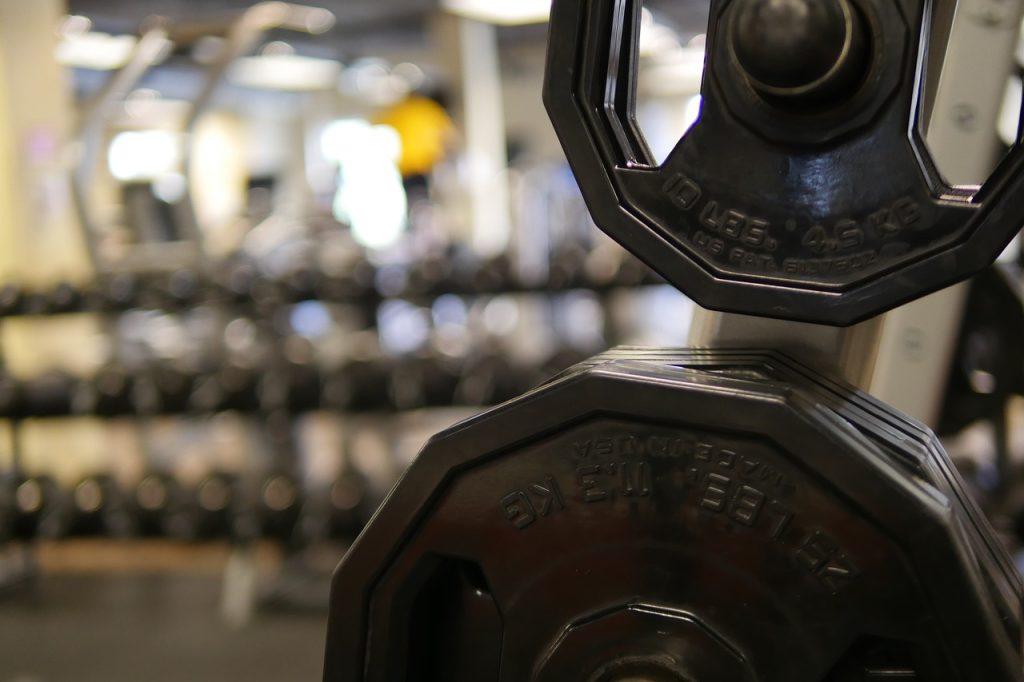 Jonge vrouw die gewichten heft in de sportschool tijdens haar training