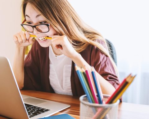 Jonge vrouw in nette werkoutfit met blazer en tas op kantoor