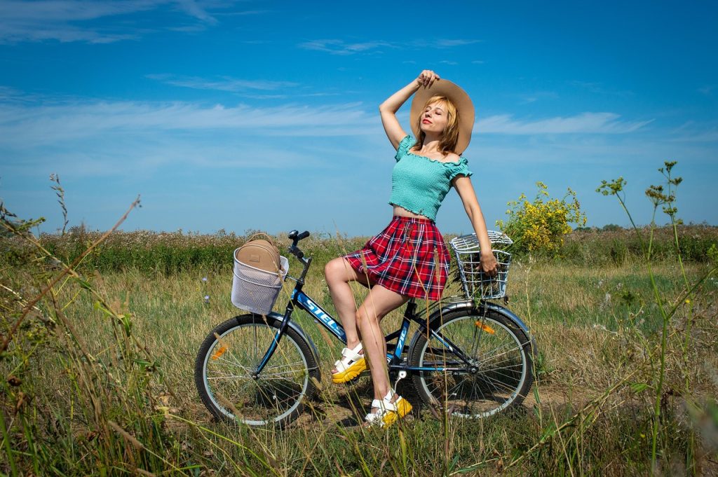 Vrouw fietst op een zomerse dag over een zonnige weg