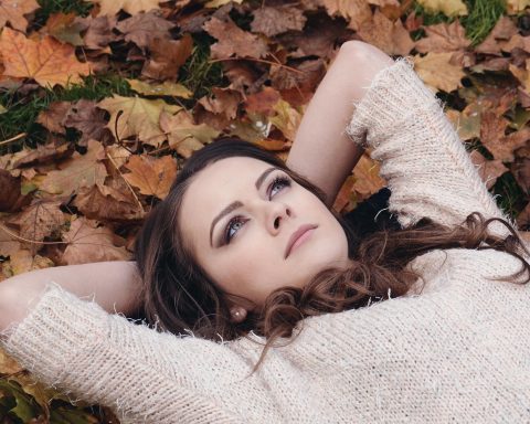 Vrouw die gezichtscrème aanbrengt in de herfst voor een spiegel