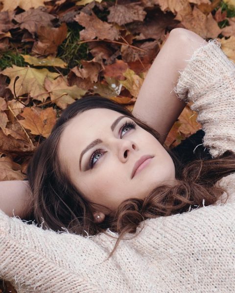 Vrouw die gezichtscrème aanbrengt in de herfst voor een spiegel