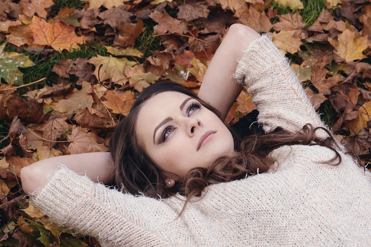 Vrouw die gezichtscrème aanbrengt in de herfst voor een spiegel