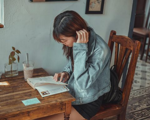 Jonge vrouw zit alleen in een café te lezen, rustig en geconcentreerd