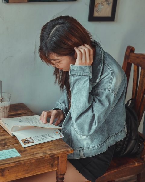 Jonge vrouw zit alleen in een café te lezen, rustig en geconcentreerd