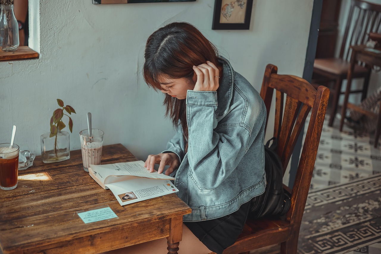 Jonge vrouw zit alleen in een café te lezen, rustig en geconcentreerd