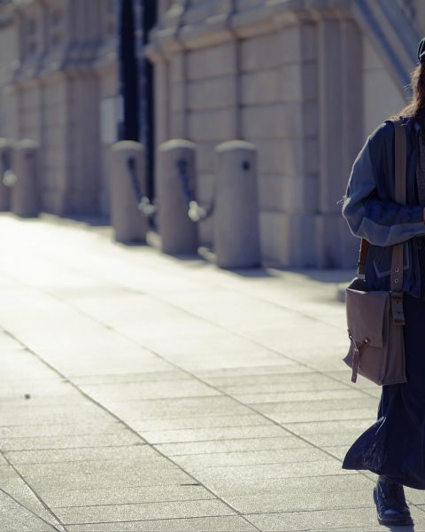 Vrouw in herfstoutfit met rotan gevlochten tas en wollen jas
