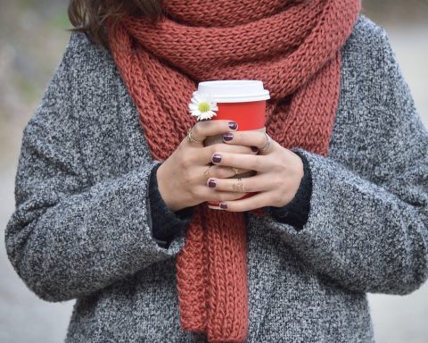 Vrouw die een roestbruine herfsttrui vasthoudt en zichzelf bekijkt in de spiegel